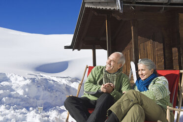 Italien, Südtirol, Seiseralm, Seniorenpaar vor Blockhütte sitzend, lächelnd, Porträt - WESTF11436