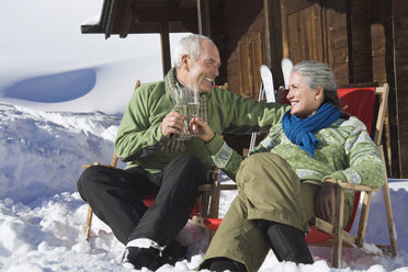 Italien, Südtirol, Seiseralm, Älteres Paar vor Blockhütte sitzend, Sektgläser haltend - WESTF11435