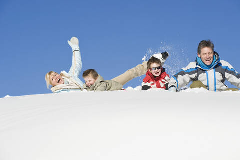 Italien, Südtirol, Seiseralm, Familie im Schnee liegend, lachend, Portrait, lizenzfreies Stockfoto