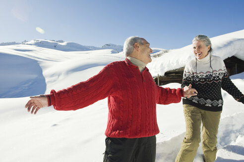 Italy, South Tyrol, Seiseralm, Senior couple in winter scenery - WESTF11385