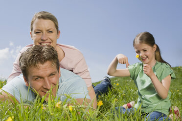 Germany, Bavaria, Munich, Couple lying in meadow, Girl (6-7) holding flower - CLF00750