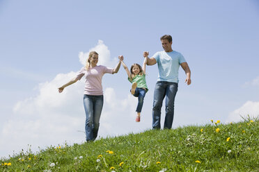 Deutschland, Bayern, München, Eltern mit Kind (6-7) beim Spaziergang auf einer Wiese - CLF00733