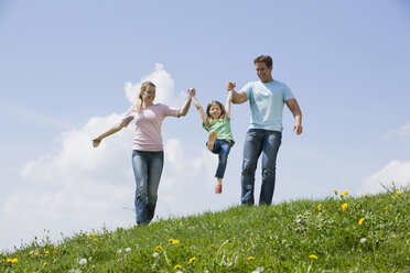 Germany, Bavaria, Munich, Parents with child (6-7) walking in meadow - CLF00733