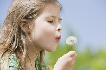 Germany, Bavaria, Munich, Girl (6-7) blowing dandelion seeds, eyes closed, side view, portrait - CLF00730