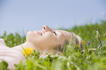 Germany, Bavaria, Munich, Young woman lying in meadow, eyes closed, portrait - CLF00726