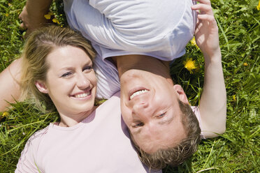 Germany, Bavaria, Munich, Young couple lying in meadow, smiling, elevated view, portrait - CLF00711