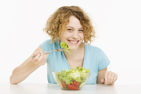 Junge Frau isst Salat, lächelnd, Porträt - CLF00830