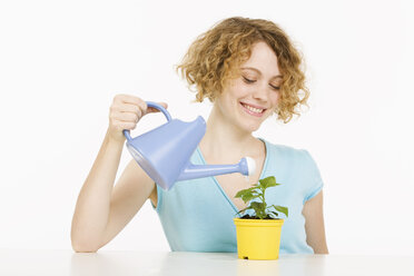 Junge Frau gießt Pflanze, lächelnd, Porträt - CLF00829