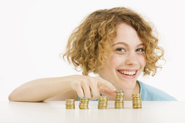 Young woman and stacked Euro coins, smiling, portrait - CLF00828