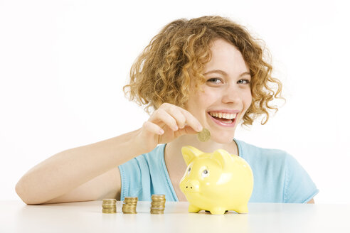 Young woman with Euro coins and piggy bank, smiling, portrait - CLF00827