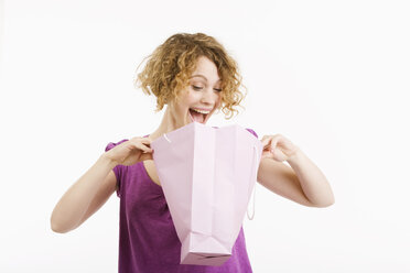 Junge Frau schaut in eine Einkaufstasche, frohlockend, Porträt - CLF00778
