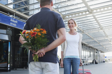 Deutschland, Leipzig-Halle, Flughafen, Mann stehend mit Blumen, Frau lächelnd - WESTF12094