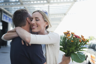 Deutschland, Leipzig-Halle, Flughafen, Pärchen umarmt sich, Mann hält Blumen - WESTF12089