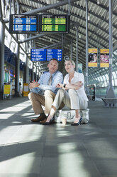 Germany, Leipzig-Halle, Airport, Businessman and businesswoman sitting on suitcase - WESTF12071