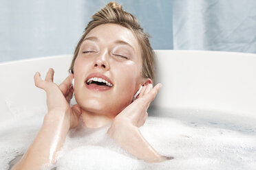 Young woman in bathtub listening to music - WESTF11999