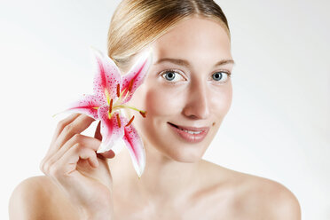 Young woman holding orchid flower, portrait - WESTF11948