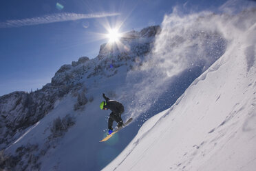 Germany, Bavaria, Chiemgau, Kampenwand, Man snowboarding downhill - FFF01066