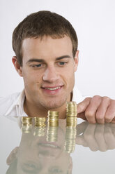 Young man counting Euro coins, portrait - RBF00094