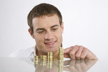 Young man counting Euro coins, portrait - RBF00093