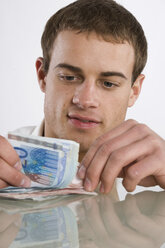 Junger Mann beim Zählen von Euro-Noten, Porträt - RBF00092