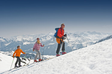 Austria, Salzburger Land, Altenmarkt, Zauchensee, Three persons cross country skiing in mountains, side view - HHF02973