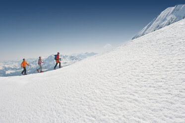 Österreich, Salzburger Land, Altenmarkt, Zauchensee, Drei Personen beim Skilanglauf in den Bergen, Seitenansicht - HHF02972