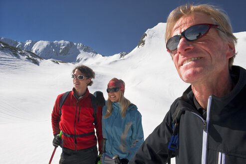 Österreich, Salzburger Land, Altenmarkt, Zauchensee, Drei Personen in verschneiter Landschaft, Mann hält Skistock, Porträt - HHF02967