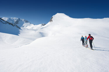 Austria, Salzburger Land, Altenmarkt, Zauchensee, Three persons cross country skiing in mountains - HHF02953