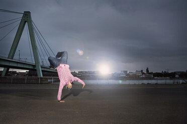 Deutschland, Köln, Junger Mann beim Breakdance, Rheinbrücke im Hintergrund - SK00014