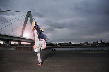 Deutschland, Köln, Junger Mann beim Breakdance, Rheinbrücke im Hintergrund - SK00011