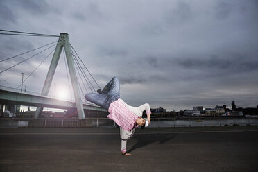Deutschland, Köln, Junger Mann beim Breakdance, Rheinbrücke im Hintergrund - SK00010