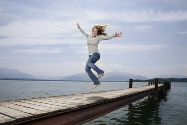 Deutschland, Chiemsee, Frau springt auf Steg - RBF00104