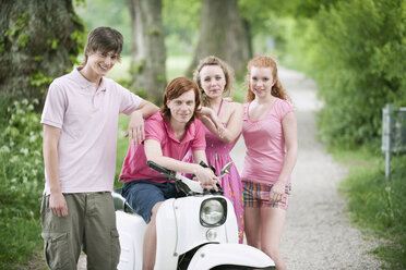 Germany, Bavaria, Four friends standing by moped, portrait - WESTF12235