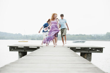 Germany, Bavaria, Ammersee, Four friends jumping on jetty - WESTF12227