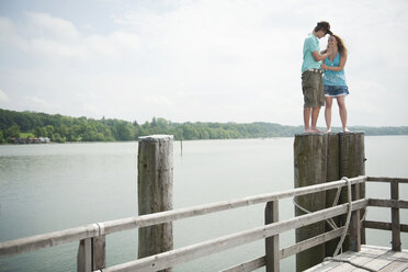 Germany, Bavaria, Ammersee, Young couple standing on wooden post - WESTF12208