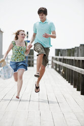 Germany, Bavaria, Ammersee, Young couple running on pier - WESTF12206