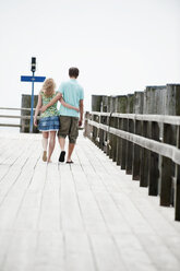 Germany, Bavaria, Ammersee, Couple walking across pier, rear view - WESTF12200