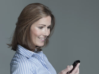 Frau mit Mobiltelefon in der Hand, Blick nach unten, Porträt - WEST12269