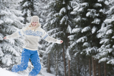 Austria, Salzburger Land, Altenmarkt, Zauchensee, Young woman jumping in snow, smiling, portrait - HHF03016