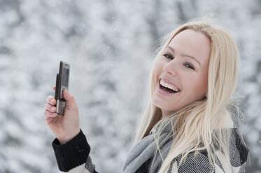 Österreich, Salzburger Land, Altenmarkt, Zauchensee, Junge Frau mit Mobiltelefon in der Hand, lachend, Porträt - HHF03013