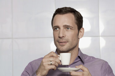 Germany, Cologne, Young man holding cup of coffee - WESTF12413