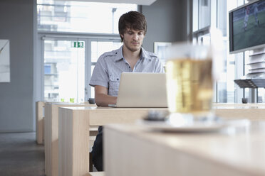 Germany, Cologne, Young man in cafe using laptop - WESTF12375