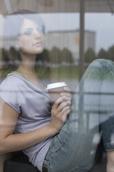 Germany, Cologne, Young woman in window of cafe - WESTF12370