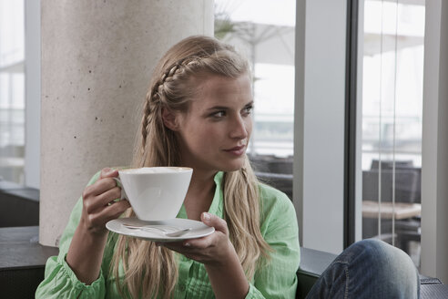 Germany, Cologne, Young woman in cafe holding cup of coffee, portrait - WESTF12350