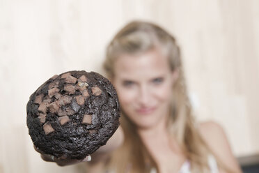 Germany, Cologne, Young woman holding cookie, close-up - WESTF12447