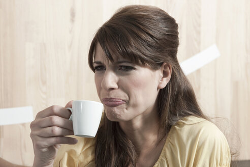 Germany, Cologne, Young woman holding cup of coffee, portrait - WESTF12442