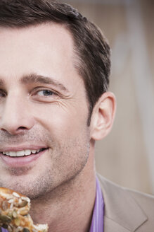 Germany, Cologne, Man holding bread roll, portrait, close-up - WESTF12431