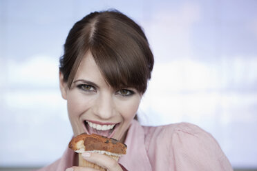 Germany, Cologne, Young woman holding muffin, portrait, close-up - WESTF12463