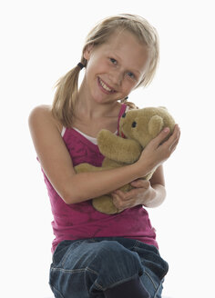 Portrait of girl (10-11) cuddling teddy bear, studio shot - WWF00973