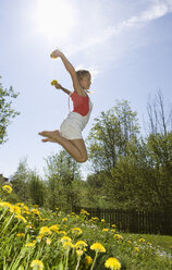 Österreich, Salzkammergut, Mädchen (10-11) springt im Garten, Seitenansicht - WWF00950